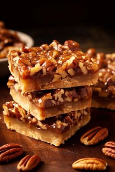 three pieces of pecan bar stacked on top of each other with pecans around them