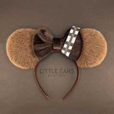 a mouse ears headband with a brown bow and white squares on the top,