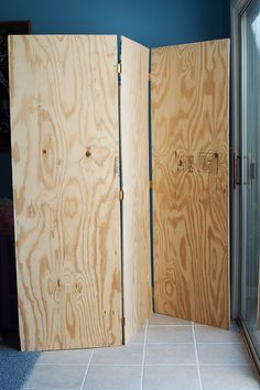 two wooden doors are open on the floor in front of a window with blue walls