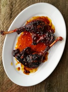 two pieces of meat on a white plate covered in sauce and ketchup sitting on top of a wooden table