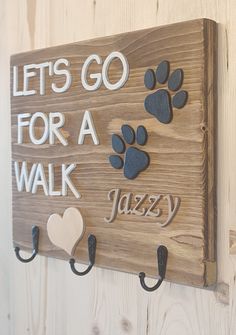 a wooden sign that says let's go for a walk with paw prints on it