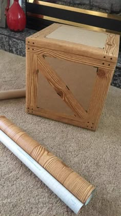 a wooden box sitting on top of a floor next to a hammer and a piece of wood