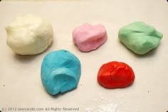 four different colored marshmallows on a white surface