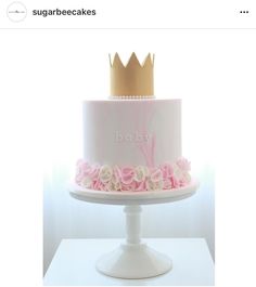 a white cake with pink flowers and a gold crown on top