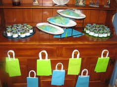 there are many bags and plates on the counter in this store display case, all decorated with green and blue paper shopping bags