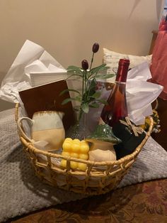 a wicker basket filled with wine, cheese and other items sitting on a bed