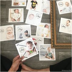 a person holding up some baby pictures in front of a wooden table with other photos on it