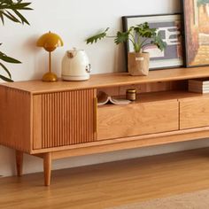 a wooden shelf with plants and pictures on it