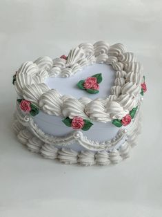 a heart shaped cake decorated with roses and braids on a white tablecloth background