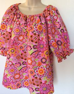 This handmade blouse is made in a 1960's style with puffy sleeves and elastic neckline. The fabric is a polyester/cotton seersucker with the wrinkling or puckering in it. It is sized 12-14 misses. The neckline and short sleeves are gathered with elastic. The print is bright floral great for spring and summer. This blouse can easily be worn by teen to adult. Multicolor Fitted Blouse With Balloon Sleeves, Fitted Multicolor Blouse With Balloon Sleeves, Fitted Multicolor Balloon Sleeve Blouse, Summer Floral Print Peasant Top With Balloon Sleeves, Cotton Peasant Top With Puff Sleeves And Floral Print, Pink Cotton Smock Blouse, Pink Floral Print Blouse With Balloon Sleeves, Pink Blouse With Balloon Sleeves And Floral Print, Pink Balloon Sleeve Blouse With Floral Print