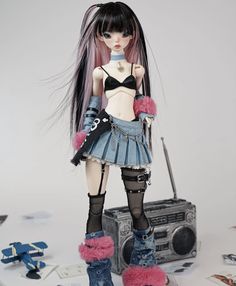 a doll with long black hair and blue boots is standing next to a boombox