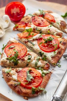 several slices of pizza with tomatoes and basil on top, sitting on a white surface