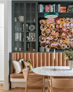 a dining room table with two chairs and a bookcase in the back wall behind it