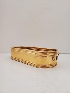 an old brass planter is sitting on a white surface with no one around it