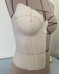 a mannequin's torso is shown with red thread on the bottom part