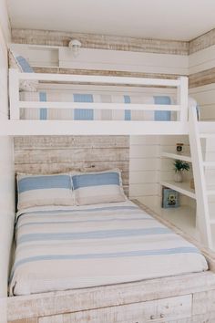 a white bunk bed with blue and white striped sheets