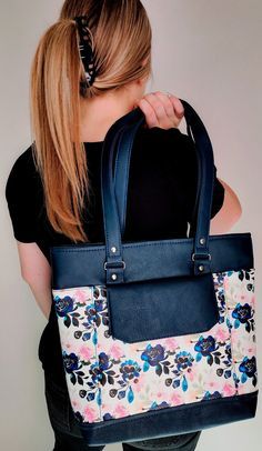 a woman carrying a blue floral bag with white and pink flowers on the front pocket