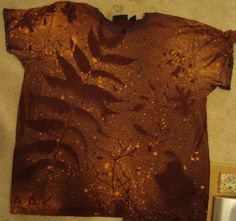 a t - shirt that has been dyed brown and is sitting on the floor next to a mirror