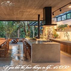 an open kitchen and dining room area with stone walls, concrete flooring and large windows