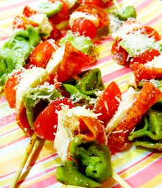 several skewers filled with meat and vegetables on a colorful striped plate, topped with parmesan cheese