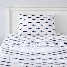 a white bed with blue sharks on it