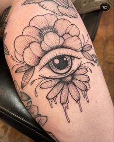 a tattoo with an eye and flowers on it