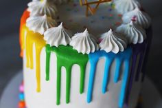 a multicolored birthday cake with icing and sprinkles on it