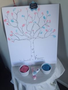 an easel with paint and brushes on it next to a tree painted on the wall