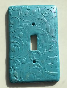 a light switch cover with swirl designs on the front and back covers in aqua blue