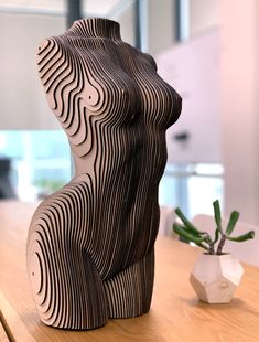 a wooden sculpture sitting on top of a table next to a potted plant