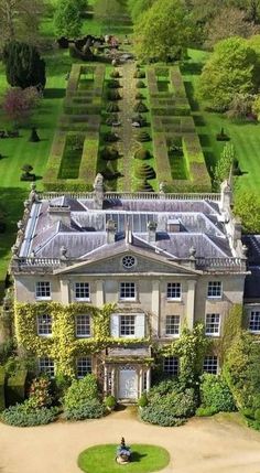 an aerial view of a large house in the middle of a lush green field