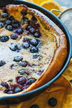 a blueberry cobbler in a cast iron skillet with lemons and powdered sugar