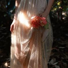 a woman in a long dress holding a flower