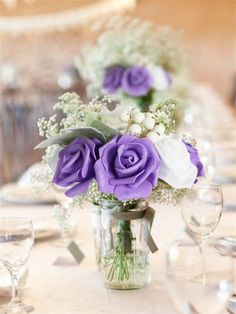 purple and white flowers in a mason jar on a dining room table with wine glasses