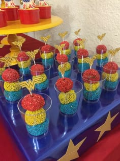 there are many cupcakes on the table with candy in them for wonder woman birthday party