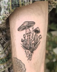 a man's leg with a mushroom tattoo on it and plants growing out of it