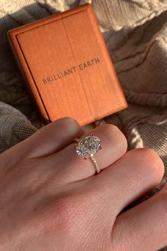 a woman's hand with a ring on it and an orange box in the background