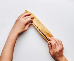 two hands are holding a piece of wood