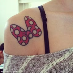 a woman's shoulder with a red and white polka dot butterfly tattoo on it