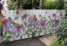 purple flowers painted on the side of a white fence with green leaves and orange centers