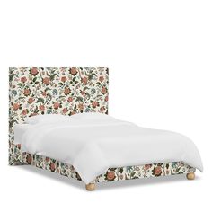 an upholstered bed with white sheets and floral headboard