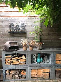 an outdoor bar with potted plants and firewood