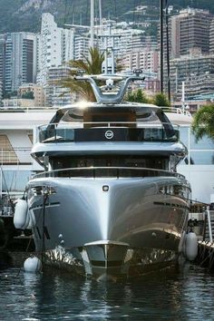 a large silver boat docked in the water next to some buildings and palm trees on top of it