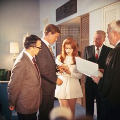 a group of people standing around each other in front of a laptop computer on a table