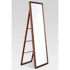 a large mirror sitting on top of a wooden floor next to a white wall mounted shelf