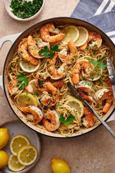 a skillet filled with pasta and shrimp, garnished with parsley on the side