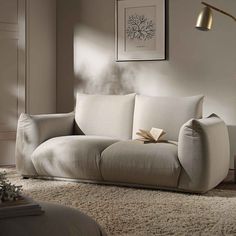 a white couch sitting on top of a rug in a living room next to a lamp