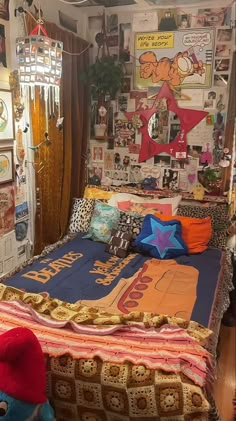 a bed with lots of pillows on top of it in a room filled with posters