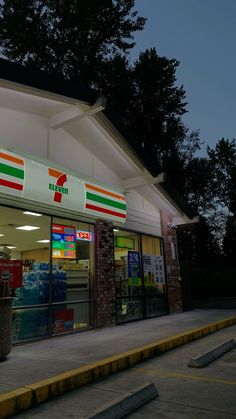 a store front at night with the lights on and signs lit up in red, white, and green