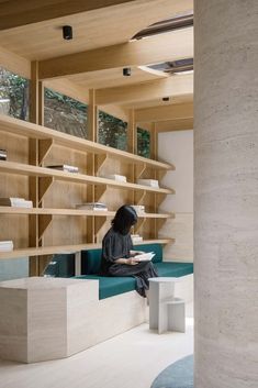 a person sitting on a bench in front of some bookshelves and shelving